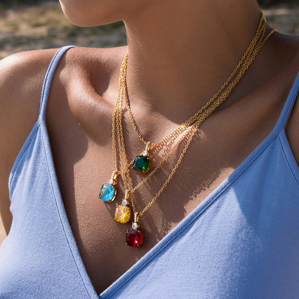 Four colored pendant necklaces layered together