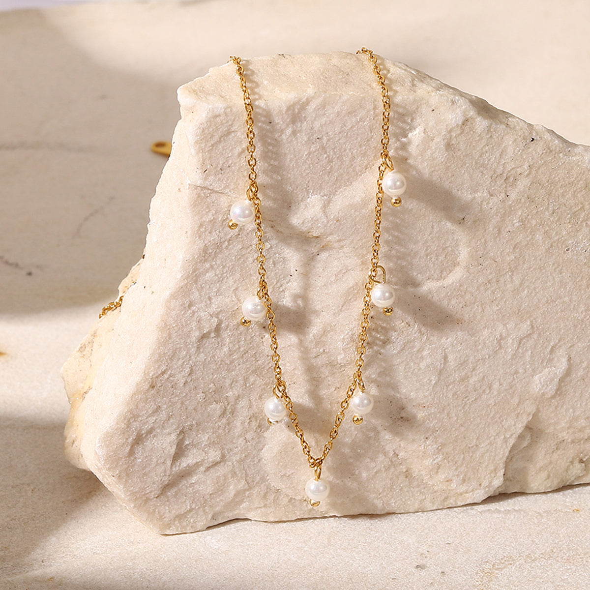 gold plated station necklace with spaced white pearl-style beads on stone