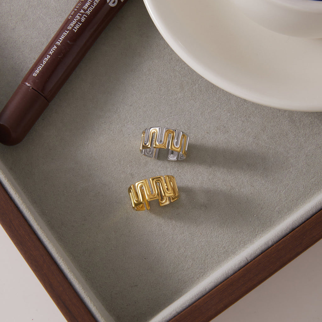 Two meander ring finishes displayed beside a cup