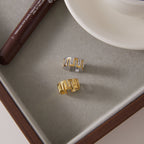 Two meander ring finishes displayed beside a cup