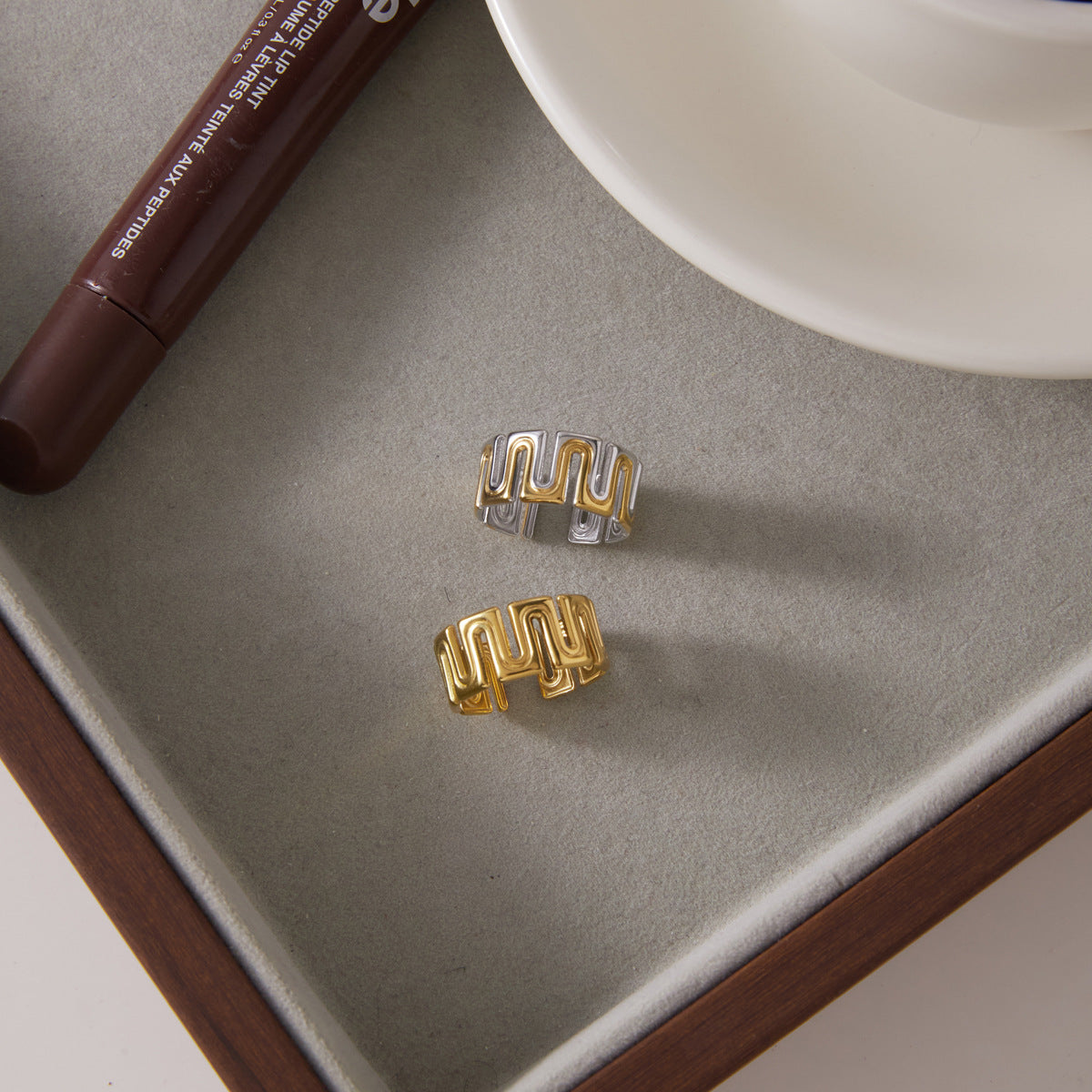Two meander ring finishes displayed beside a cup