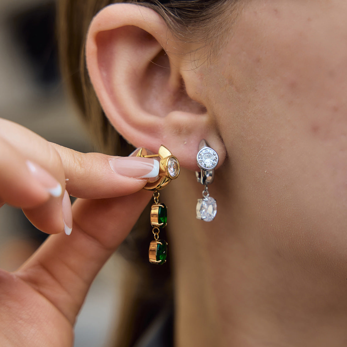 Model showing clear and green asymmetric earrings