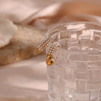 gold plated pearl huggie earrings displayed on clear glass