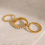 Gold-tone connected rings laid open showing the accented middle band
