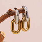 two-tone interlocking oval-link drop earrings on wood