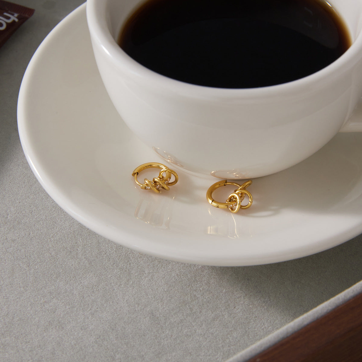 Pair of small multi-ring hoops beside a coffee cup