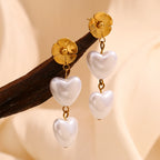 gold plated flower and heart pearl drop earrings on wood