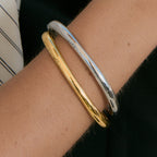 Gold and silver tone curved bangles worn together