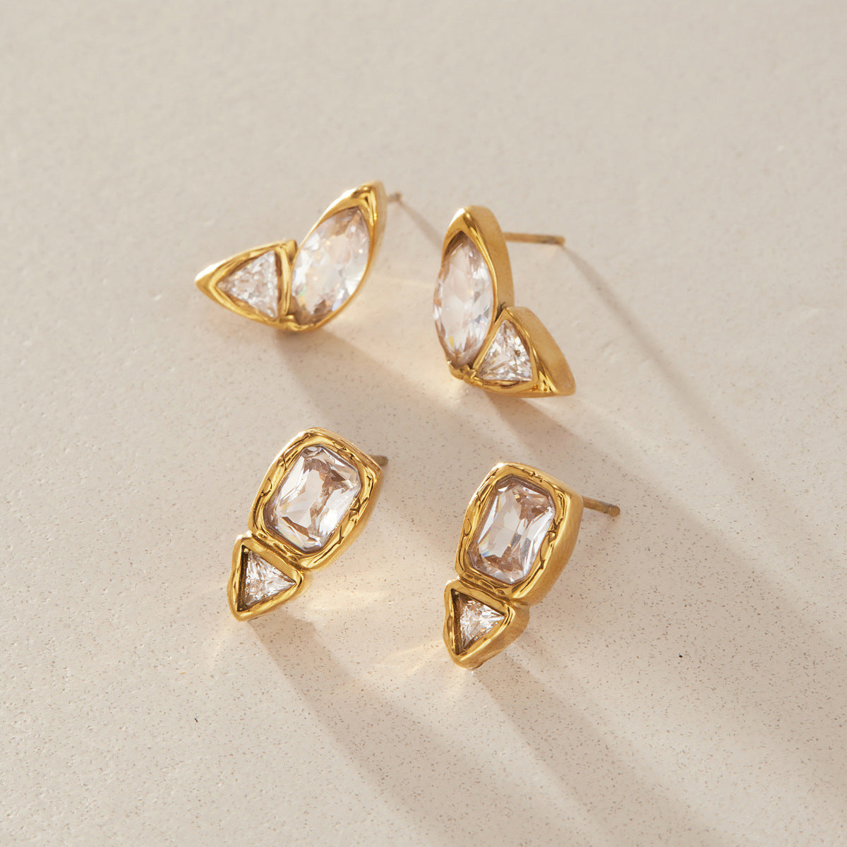 Marquise and rectangular two-stone studs on a textured surface