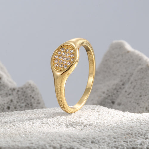 angled gold plated pavé oval signet ring on a stone display