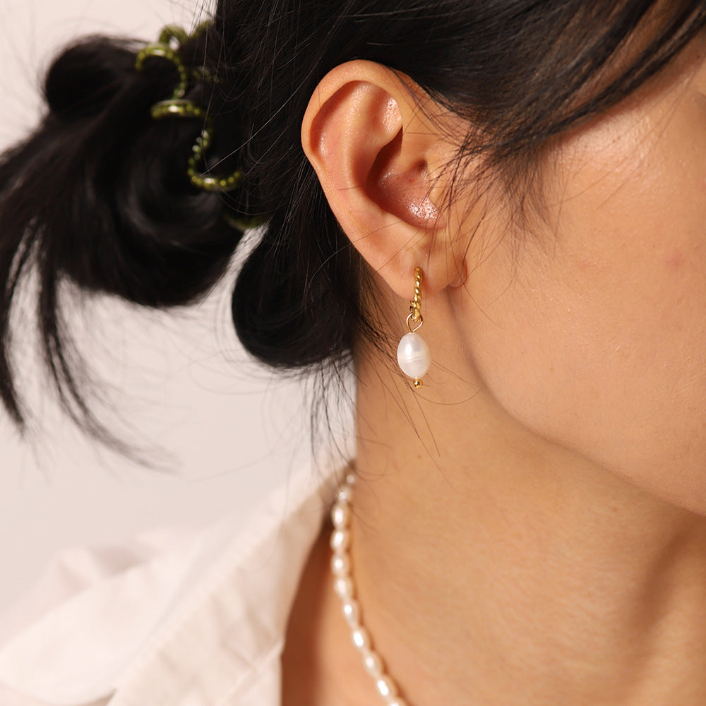Side wearing view of the twisted hoop and oval pearl pendant