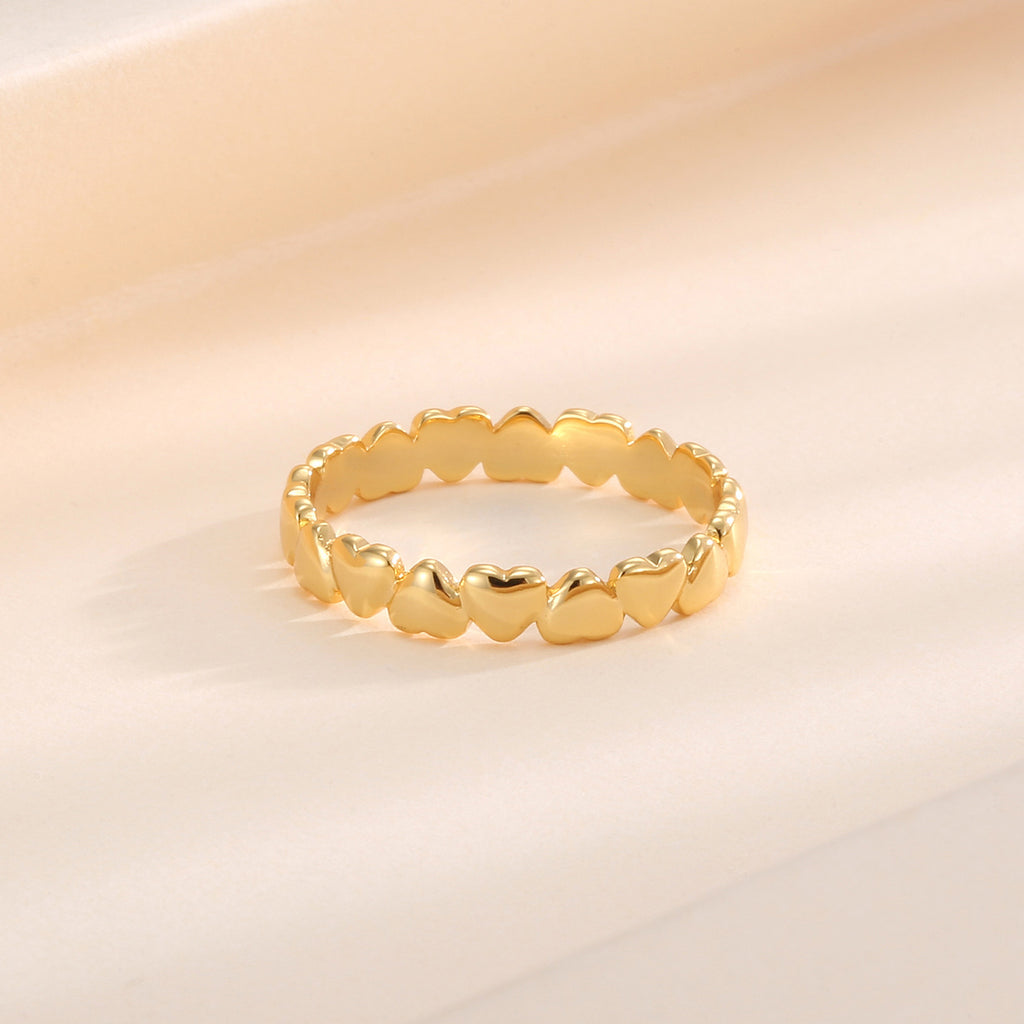 gold plated polished heart band ring resting on a warm backdrop