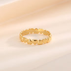 gold plated polished heart band ring resting on a warm backdrop