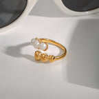 Three white beads facing three polished balls on the open ring