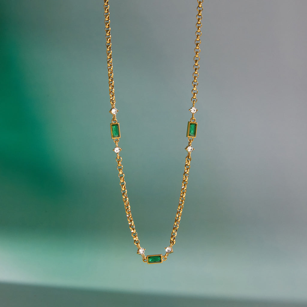 Green station necklace hanging against a plain background