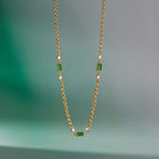 Green station necklace hanging against a plain background