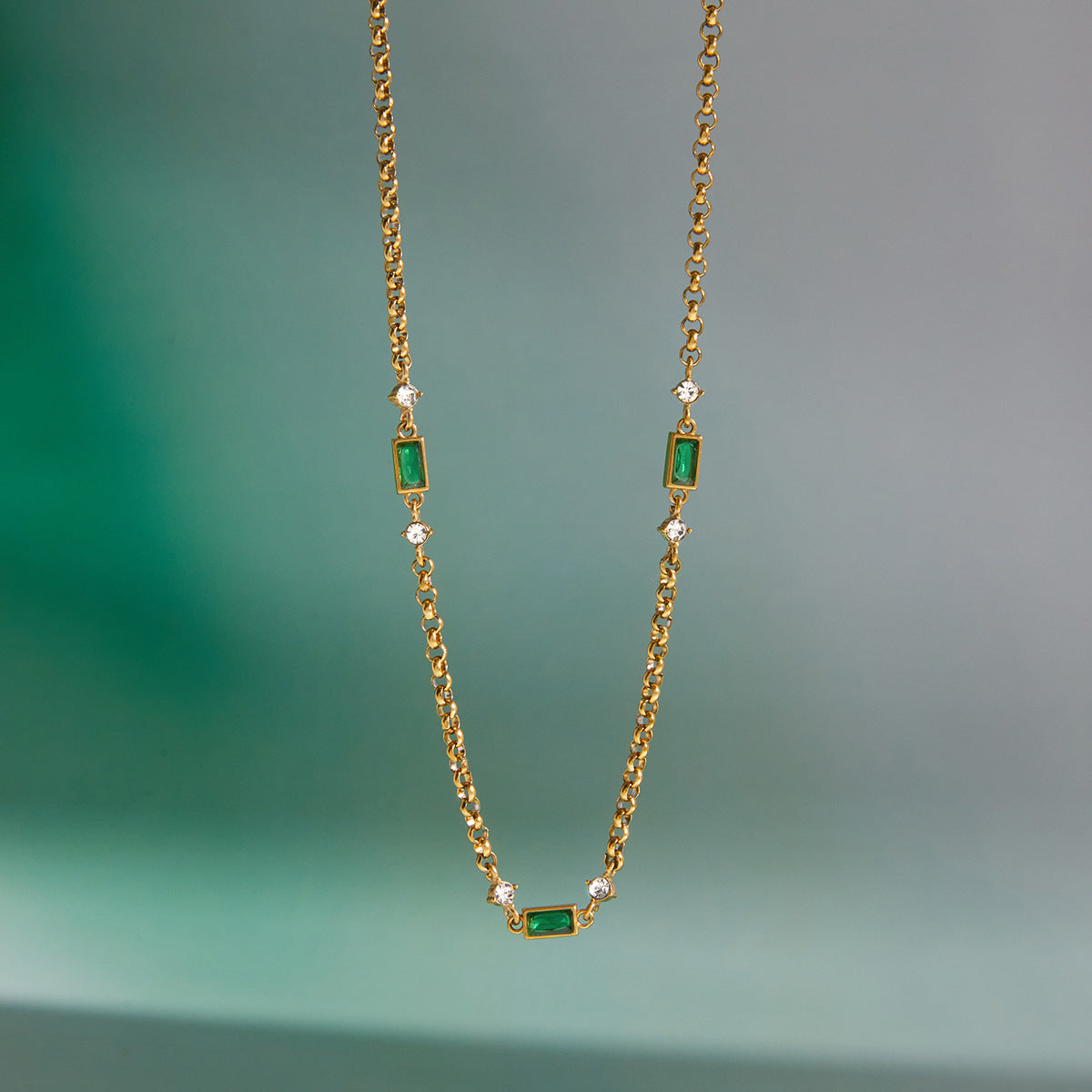 Green station necklace hanging against a plain background