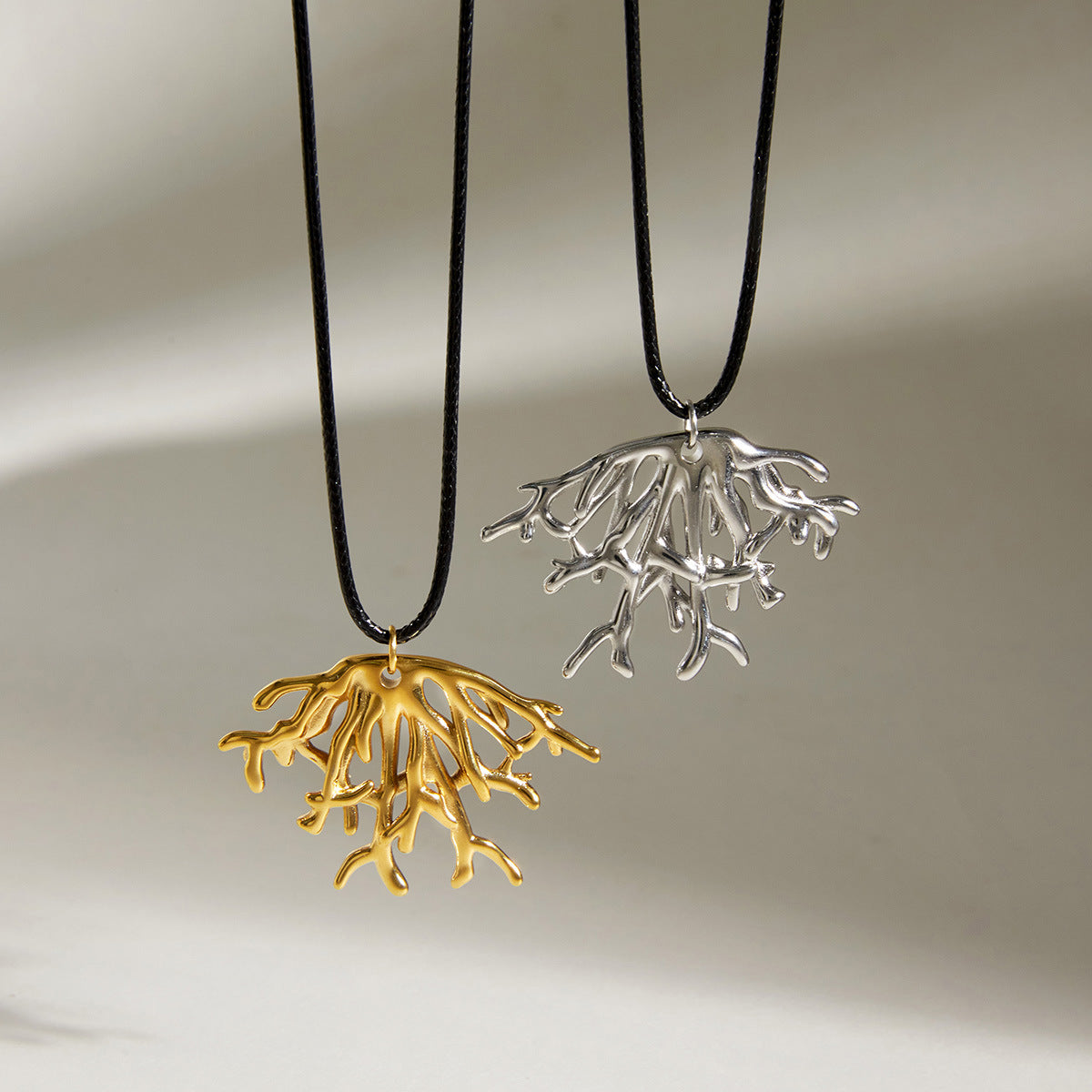 Both coral pendants hanging against a pale background