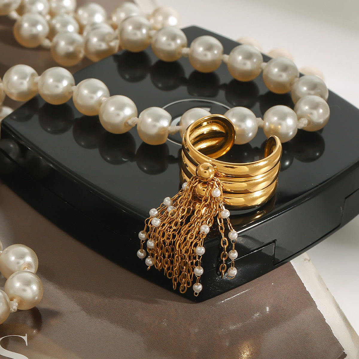 Tassel ring arranged beside pearl-style jewelry