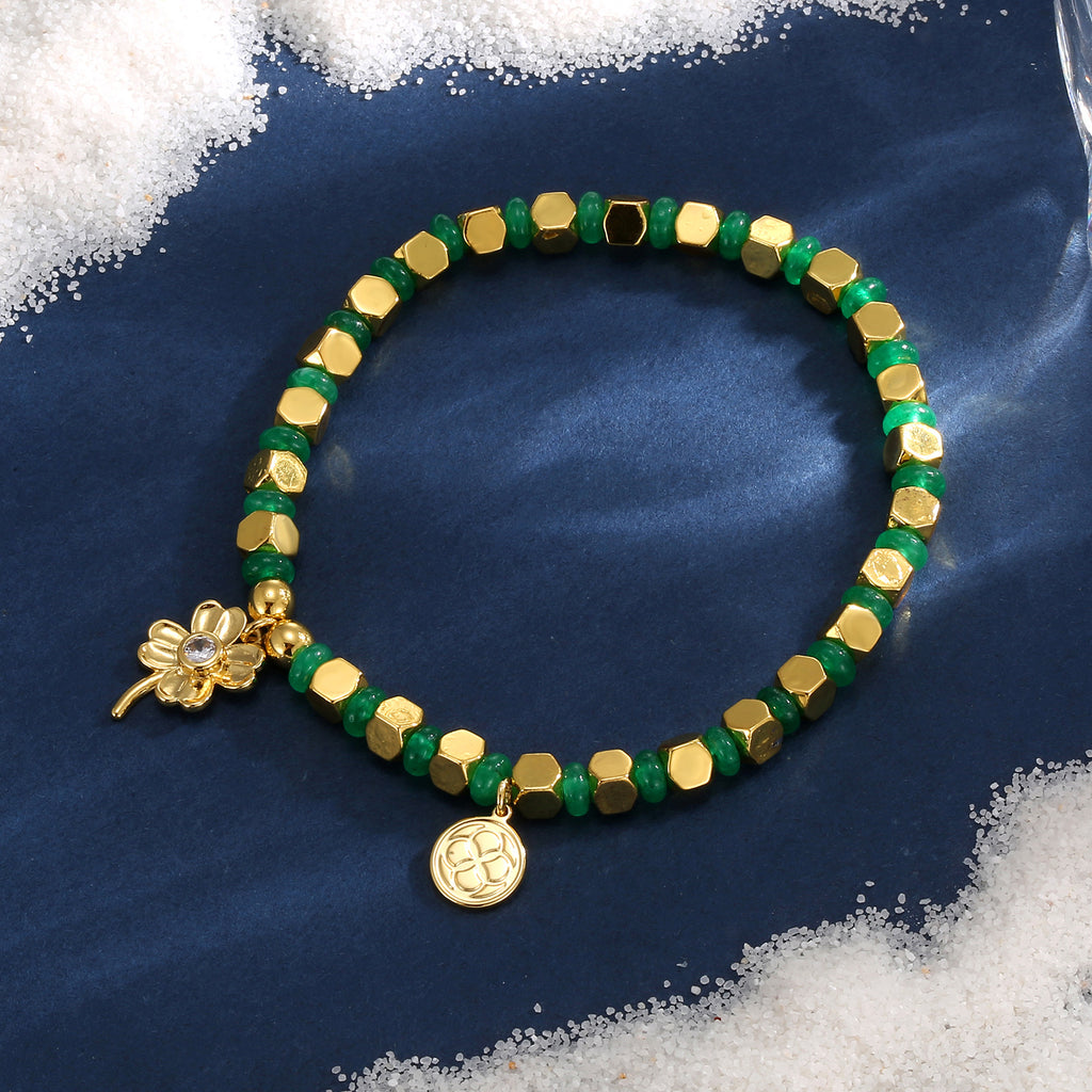 green and gold clover charm bead bracelet on a blue display