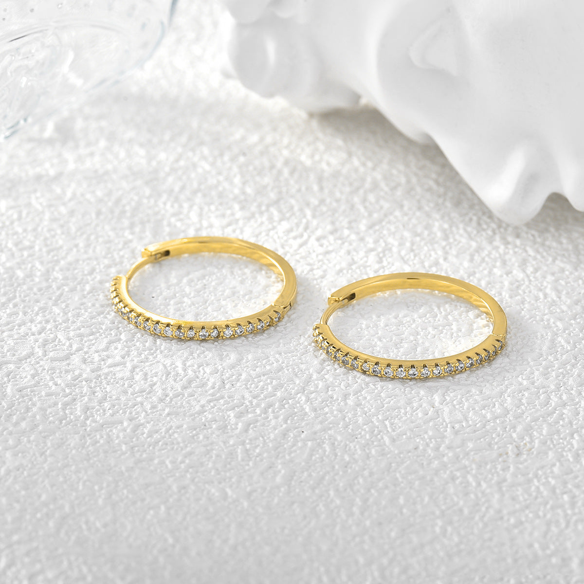 pair of slim pavé zirconia hoops on white fabric