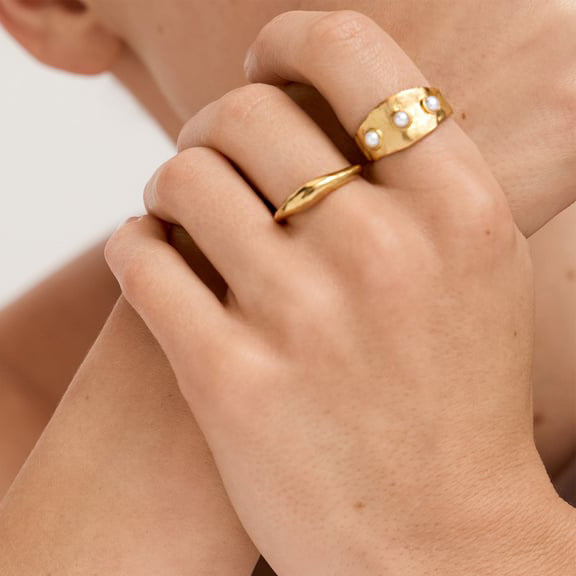 Wide gold plated band with white accents worn on a hand
