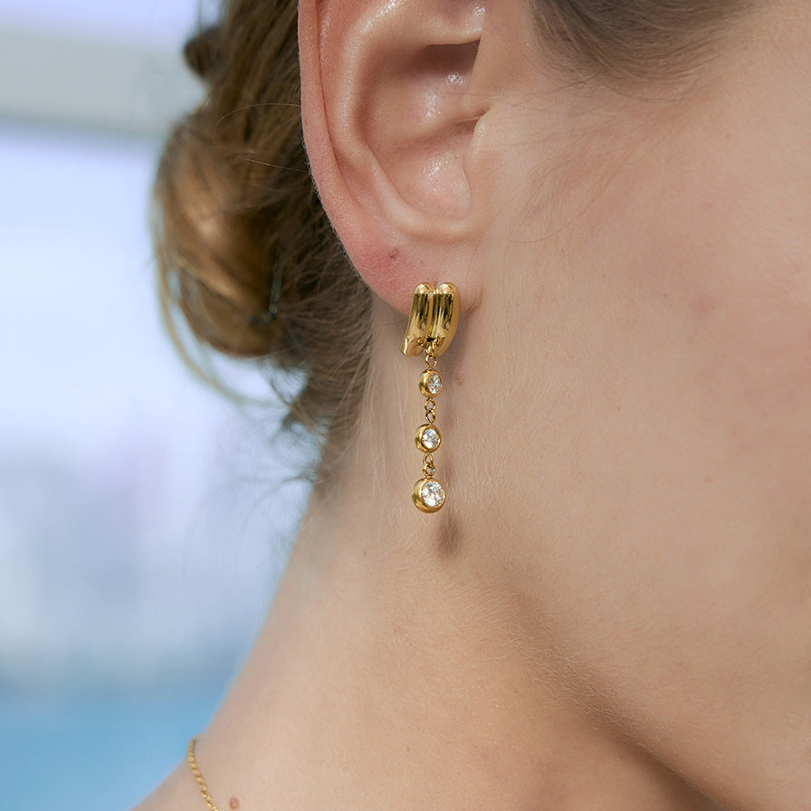 Double-ridge stud and dangling bezels worn close-up
