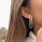 angled view of gold plated hoop with twin clear stone chains