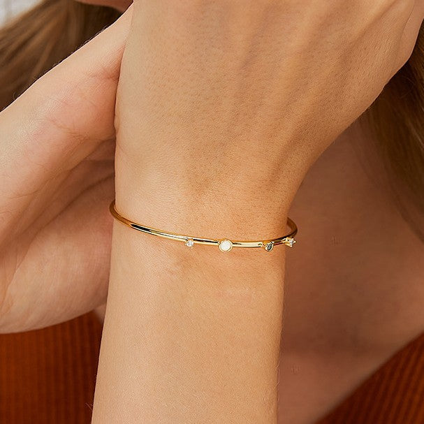 close wrist view of asymmetrical stations on gold plated cuff