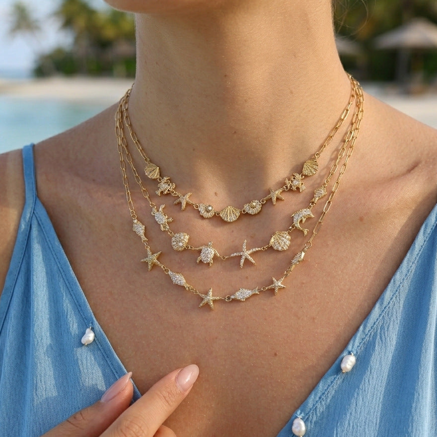 Three marine charm necklaces layered on a model