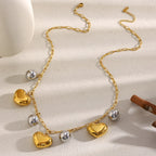 two-tone stainless steel heart charm necklace arranged on satin