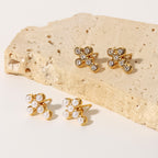 Gold-tone cross stud earrings with clear and pearl-look accents on stone