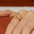 triple crossover band ring worn with an orange knit sleeve
