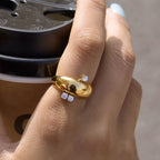 Gold tone dome ring with offset clear stones worn on a hand