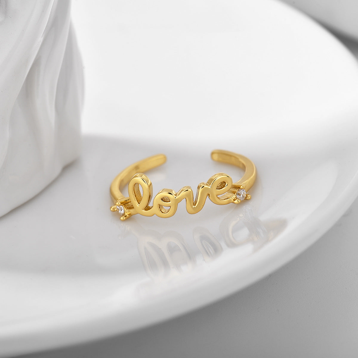 gold plated message ring displayed on a white dish