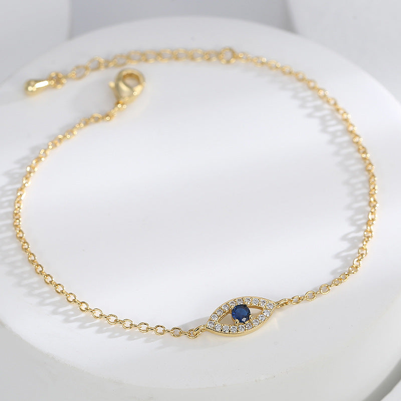 angled view of fine-chain evil eye bracelet with blue center stone