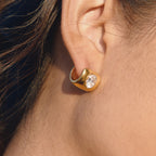 side view of broad gold plated clear-stone huggie earring
