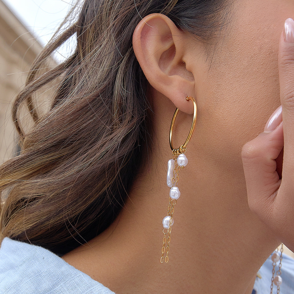 Long faux pearl and chain tassel hoop earring shown worn from the side