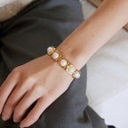 Gold-tone cuff with framed white beads shown on the wrist