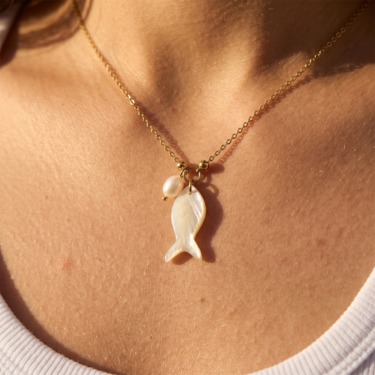 White fish pendant and small bead accent shown at neckline