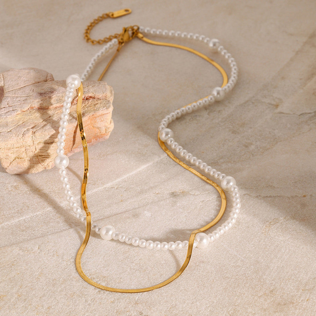 White bead strand and gold flat chain layered on a stone display