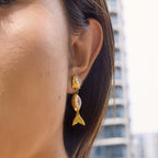 Gold tone fish drop earring worn in profile
