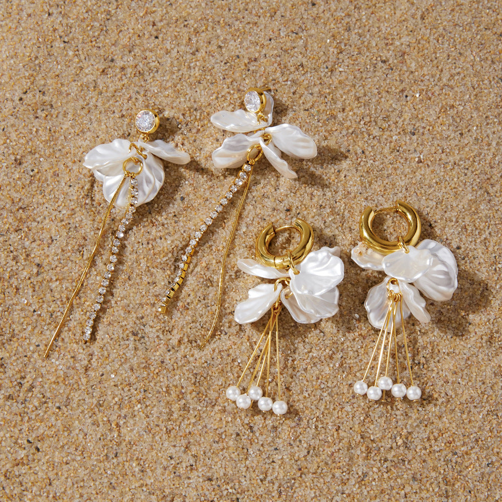 Two floral earring pairs arranged on sand