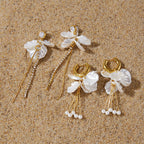 Two floral earring pairs arranged on sand