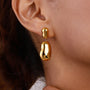 model wearing gold plated sculptural pebble drop earrings
