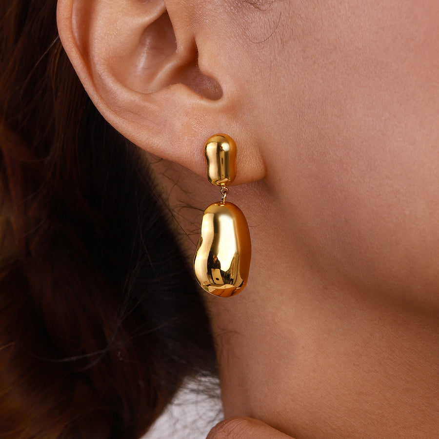 model wearing gold plated sculptural pebble drop earrings