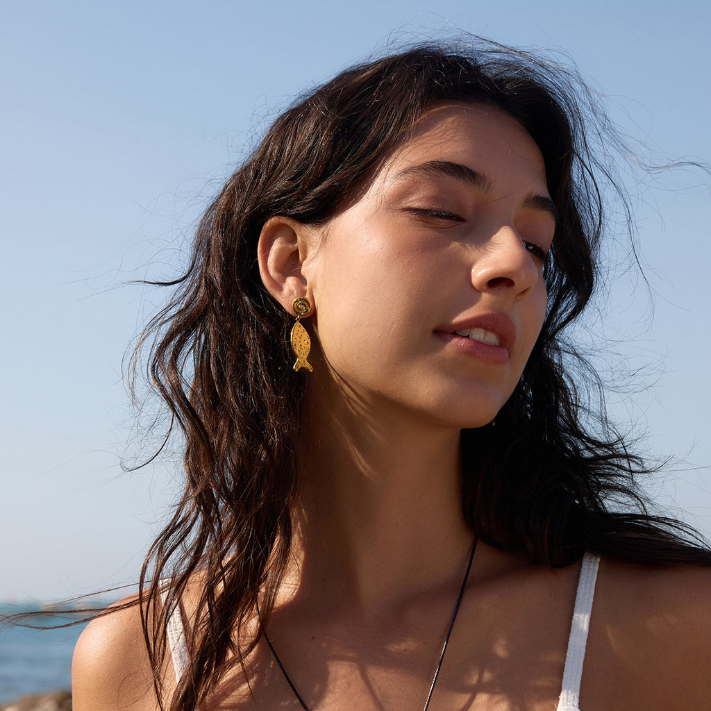 Gold-tone fish earrings shown in profile