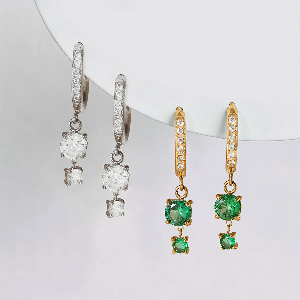 Silver tone clear-drop and gold tone green-drop huggie earrings together