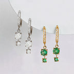 Silver tone clear-drop and gold tone green-drop huggie earrings together