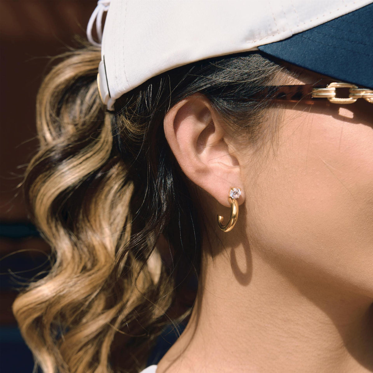 side view of clear stone stud earrings with open C-shaped drops
